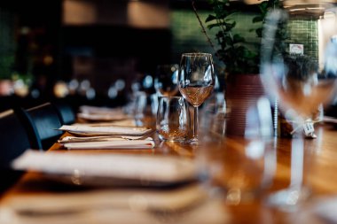 Şatafatlı yemek masaları ve cam eşyalar, bardağa şarap doldurmak. Güzel bulanık arkaplan. Tatil düğünü için hazırlık. Lüks bir restoran..