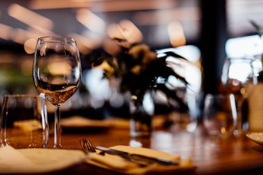 Şatafatlı yemek masaları ve cam eşyalar, bardağa şarap doldurmak. Güzel bulanık arkaplan. Tatil düğünü için hazırlık. Lüks bir restoran..