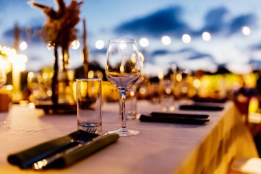 Şatafatlı yemek masaları ve cam eşyalar, bardağa şarap doldurmak. Güzel bulanık arkaplan. Tatil düğünü için hazırlık. Lüks bir restoran..