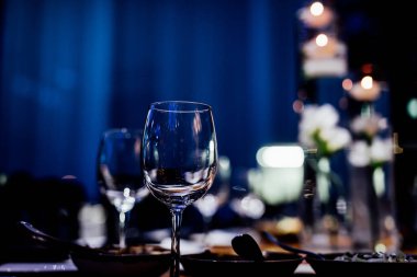 Şatafatlı yemek masaları ve cam eşyalar, bardağa şarap doldurmak. Güzel bulanık arkaplan. Tatil düğünü için hazırlık. Lüks bir restoran..