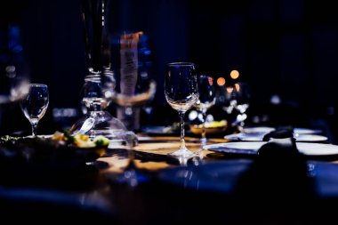 Şatafatlı yemek masaları ve cam eşyalar, bardağa şarap doldurmak. Güzel bulanık arkaplan. Tatil düğünü için hazırlık. Lüks bir restoran..