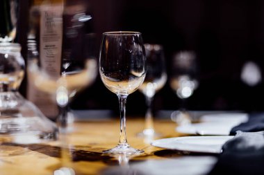 Şatafatlı yemek masaları ve cam eşyalar, bardağa şarap doldurmak. Güzel bulanık arkaplan. Tatil düğünü için hazırlık. Lüks bir restoran..
