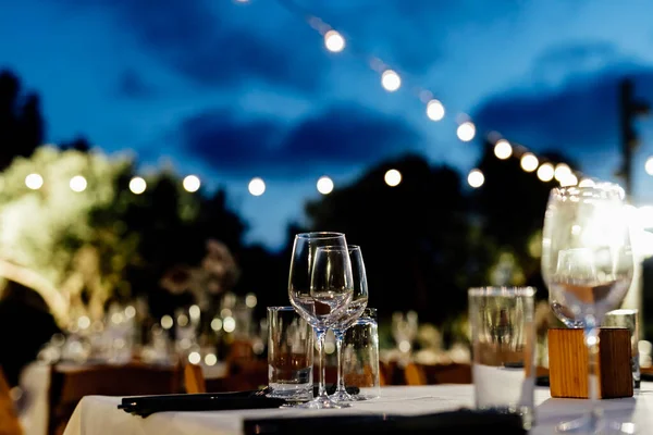Şatafatlı yemek masaları ve cam eşyalar, bardağa şarap doldurmak. Güzel bulanık arkaplan. Tatil düğünü için hazırlık. Lüks bir restoran..