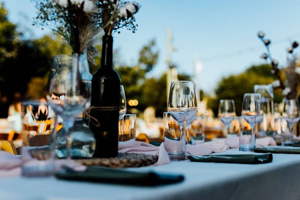 Şatafatlı yemek masaları ve cam eşyalar, bardağa şarap doldurmak. Güzel bulanık arkaplan. Tatil düğünü için hazırlık. Lüks bir restoran..