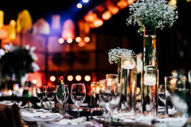 Şatafatlı yemek masaları ve cam eşyalar, bardağa şarap doldurmak. Güzel bulanık arkaplan. Tatil düğünü için hazırlık. Lüks bir restoran..