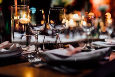 Şatafatlı yemek masaları ve cam eşyalar, bardağa şarap doldurmak. Güzel bulanık arkaplan. Tatil düğünü için hazırlık. Lüks bir restoran..