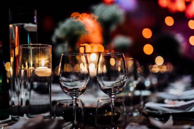 Şatafatlı yemek masaları ve cam eşyalar, bardağa şarap doldurmak. Güzel bulanık arkaplan. Tatil düğünü için hazırlık. Lüks bir restoran..