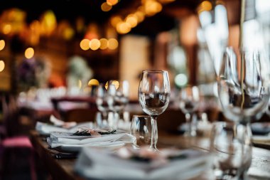Şatafatlı yemek masaları ve cam eşyalar, bardağa şarap doldurmak. Güzel bulanık arkaplan. Tatil düğünü için hazırlık. Lüks bir restoran..