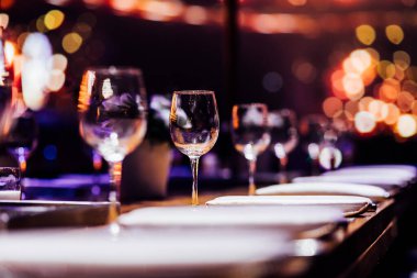 Şatafatlı yemek masaları ve cam eşyalar, bardağa şarap doldurmak. Güzel bulanık arkaplan. Tatil düğünü için hazırlık. Lüks bir restoran..