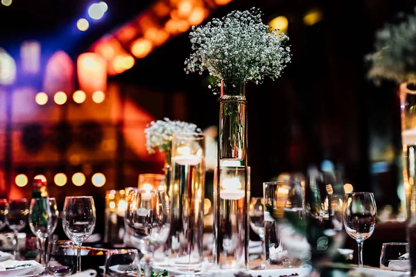 Şatafatlı yemek masaları ve cam eşyalar, bardağa şarap doldurmak. Güzel bulanık arkaplan. Tatil düğünü için hazırlık. Lüks bir restoran..