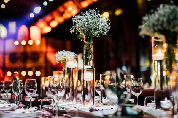 Şatafatlı yemek masaları ve cam eşyalar, bardağa şarap doldurmak. Güzel bulanık arkaplan. Tatil düğünü için hazırlık. Lüks bir restoran..