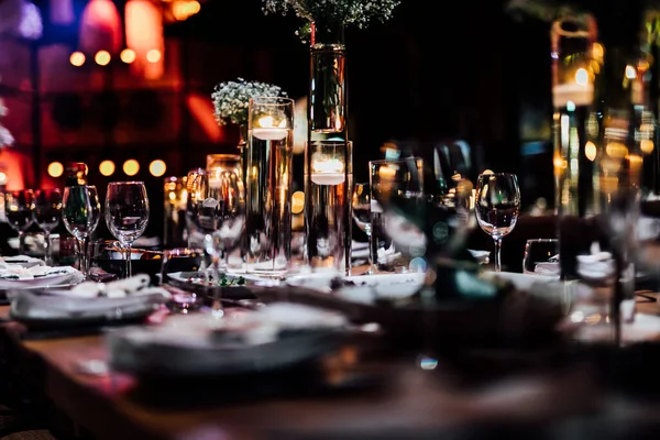 Şatafatlı yemek masaları ve cam eşyalar, bardağa şarap doldurmak. Güzel bulanık arkaplan. Tatil düğünü için hazırlık. Lüks bir restoran..