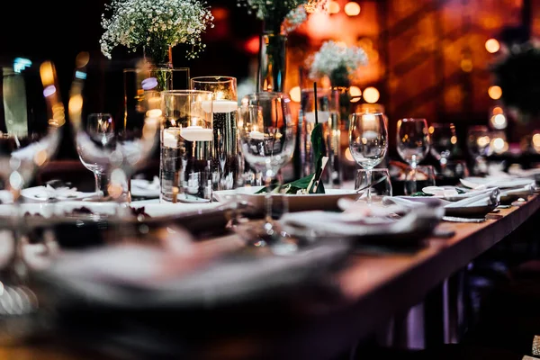 Şatafatlı yemek masaları ve cam eşyalar, bardağa şarap doldurmak. Güzel bulanık arkaplan. Tatil düğünü için hazırlık. Lüks bir restoran..