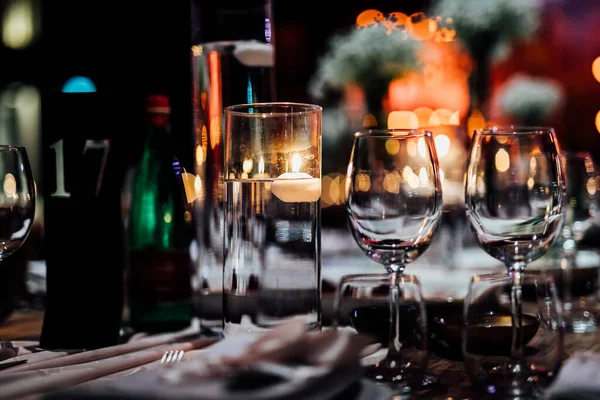 Şatafatlı yemek masaları ve cam eşyalar, bardağa şarap doldurmak. Güzel bulanık arkaplan. Tatil düğünü için hazırlık. Lüks bir restoran..