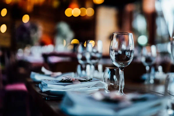 Şatafatlı yemek masaları ve cam eşyalar, bardağa şarap doldurmak. Güzel bulanık arkaplan. Tatil düğünü için hazırlık. Lüks bir restoran..