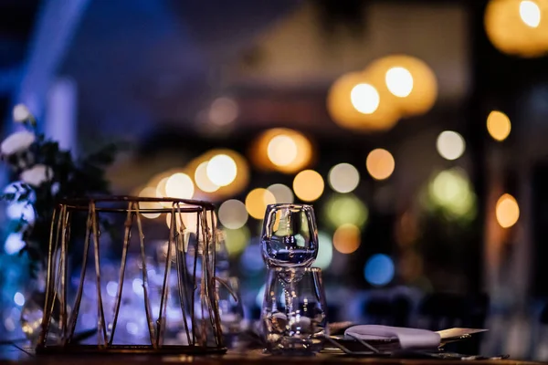 Şatafatlı yemek masaları ve cam eşyalar, bardağa şarap doldurmak. Güzel bulanık arkaplan. Tatil düğünü için hazırlık. Lüks bir restoran..