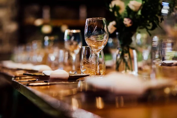 Şatafatlı yemek masaları ve cam eşyalar, bardağa şarap doldurmak. Güzel bulanık arkaplan. Tatil düğünü için hazırlık. Lüks bir restoran..