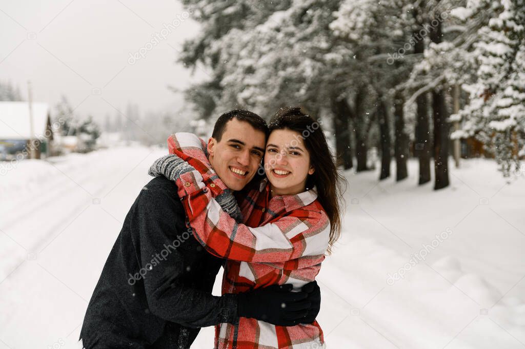 Loving couple in shirt on a winter walk. Man and woman having fun in the frosty forest. Romantic date in winter time.Christmas mood of a young family.Winter lovestory