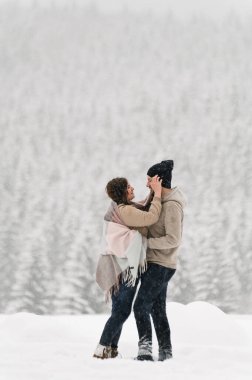 Kışın yürü. Kucaklaşan çift kar yağışı yapıyor. Erkek ve kadın soğuk ormanda eğleniyor. Kışın romantik bir randevu. Genç bir ailenin Noel havası. Aşk ve eğlence konsepti