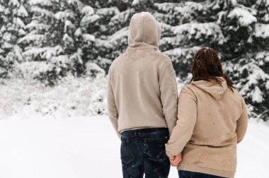 Kışın yürü. Kucaklaşan çift kar yağışı yapıyor. Erkek ve kadın soğuk ormanda eğleniyor. Kışın romantik bir randevu. Genç bir ailenin Noel havası. Aşk ve eğlence konsepti