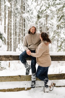 Kışın yürü. Kucaklaşan çift kar yağışı yapıyor. Erkek ve kadın soğuk ormanda eğleniyor. Kışın romantik bir randevu. Genç bir ailenin Noel havası. Aşk ve eğlence konsepti