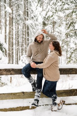Kışın yürü. Kucaklaşan çift kar yağışı yapıyor. Erkek ve kadın soğuk ormanda eğleniyor. Kışın romantik bir randevu. Genç bir ailenin Noel havası. Aşk ve eğlence konsepti