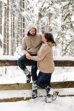 Kışın yürü. Kucaklaşan çift kar yağışı yapıyor. Erkek ve kadın soğuk ormanda eğleniyor. Kışın romantik bir randevu. Genç bir ailenin Noel havası. Aşk ve eğlence konsepti