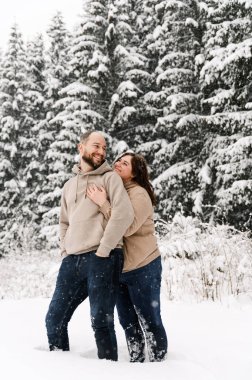 Kışın yürü. Kucaklaşan çift kar yağışı yapıyor. Erkek ve kadın soğuk ormanda eğleniyor. Kışın romantik bir randevu. Genç bir ailenin Noel havası. Aşk ve eğlence konsepti
