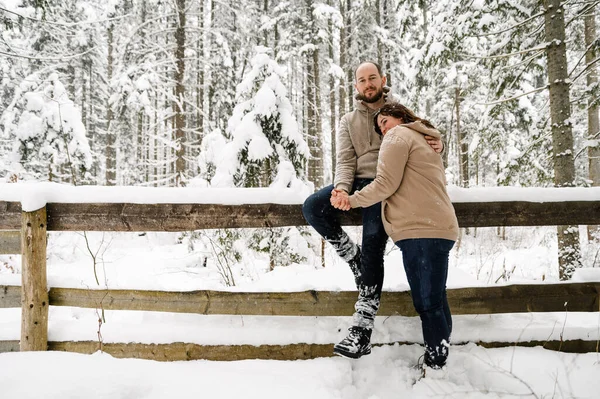 Kışın yürü. Kucaklaşan çift kar yağışı yapıyor. Erkek ve kadın soğuk ormanda eğleniyor. Kışın romantik bir randevu. Genç bir ailenin Noel havası. Aşk ve eğlence konsepti