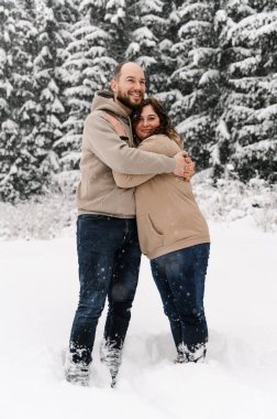 Kışın yürü. Kucaklaşan çift kar yağışı yapıyor. Erkek ve kadın soğuk ormanda eğleniyor. Kışın romantik bir randevu. Genç bir ailenin Noel havası. Aşk ve eğlence konsepti