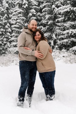 Kışın yürü. Kucaklaşan çift kar yağışı yapıyor. Erkek ve kadın soğuk ormanda eğleniyor. Kışın romantik bir randevu. Genç bir ailenin Noel havası. Aşk ve eğlence konsepti