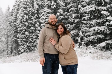 Kışın yürü. Kucaklaşan çift kar yağışı yapıyor. Erkek ve kadın soğuk ormanda eğleniyor. Kışın romantik bir randevu. Genç bir ailenin Noel havası. Aşk ve eğlence konsepti