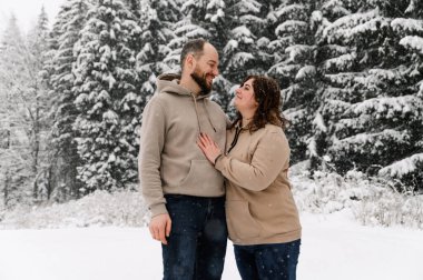 Kışın yürü. Kucaklaşan çift kar yağışı yapıyor. Erkek ve kadın soğuk ormanda eğleniyor. Kışın romantik bir randevu. Genç bir ailenin Noel havası. Aşk ve eğlence konsepti