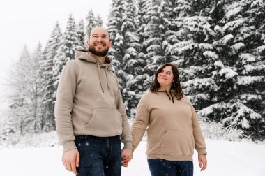 Kışın yürü. Kucaklaşan çift kar yağışı yapıyor. Erkek ve kadın soğuk ormanda eğleniyor. Kışın romantik bir randevu. Genç bir ailenin Noel havası. Aşk ve eğlence konsepti