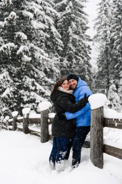 Kışın yürü. Kucaklaşan çift kar yağışı yapıyor. Erkek ve kadın soğuk ormanda eğleniyor. Kışın romantik bir randevu. Genç bir ailenin Noel havası. Aşk ve eğlence konsepti