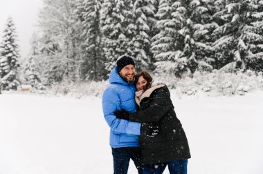 Kışın yürü. Kucaklaşan çift kar yağışı yapıyor. Erkek ve kadın soğuk ormanda eğleniyor. Kışın romantik bir randevu. Genç bir ailenin Noel havası. Aşk ve eğlence konsepti