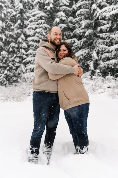 Kışın yürü. Kucaklaşan çift kar yağışı yapıyor. Erkek ve kadın soğuk ormanda eğleniyor. Kışın romantik bir randevu. Genç bir ailenin Noel havası. Aşk ve eğlence konsepti