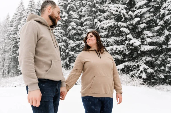 Kışın yürü. Kucaklaşan çift kar yağışı yapıyor. Erkek ve kadın soğuk ormanda eğleniyor. Kışın romantik bir randevu. Genç bir ailenin Noel havası. Aşk ve eğlence konsepti