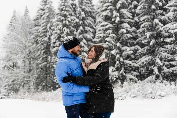 Kışın yürü. Kucaklaşan çift kar yağışı yapıyor. Erkek ve kadın soğuk ormanda eğleniyor. Kışın romantik bir randevu. Genç bir ailenin Noel havası. Aşk ve eğlence konsepti