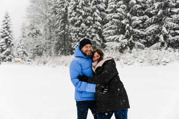 Kışın yürü. Kucaklaşan çift kar yağışı yapıyor. Erkek ve kadın soğuk ormanda eğleniyor. Kışın romantik bir randevu. Genç bir ailenin Noel havası. Aşk ve eğlence konsepti