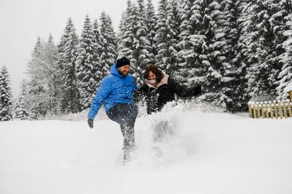Kışın yürü. Kucaklaşan çift kar yağışı yapıyor. Erkek ve kadın soğuk ormanda eğleniyor. Kışın romantik bir randevu. Genç bir ailenin Noel havası. Aşk ve eğlence konsepti