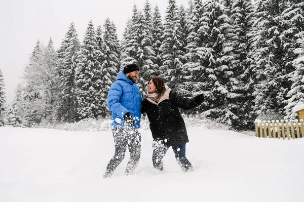 Kışın yürü. Kucaklaşan çift kar yağışı yapıyor. Erkek ve kadın soğuk ormanda eğleniyor. Kışın romantik bir randevu. Genç bir ailenin Noel havası. Aşk ve eğlence konsepti