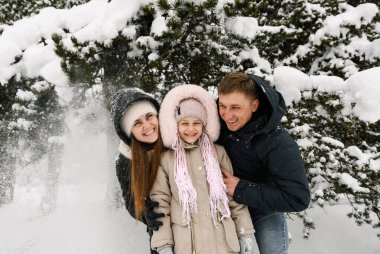 Kış ormanında neşeli mutlu bir ailenin portresi. Anne, baba ve kızı karla oynuyor. Birlikte vakit geçirmenin tadını çıkarıyorum. Aile kavramı