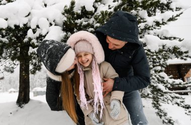 Kış ormanında neşeli mutlu bir ailenin portresi. Anne, baba ve kızı karla oynuyorlar. Birlikte vakit geçirmenin tadını çıkarıyorlar. Aile kavramı
