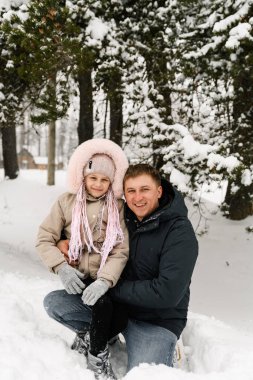 Mutlu aile kış ormanlarında eğleniyor. Baba ve kızı sarılıp karla oynuyorlar. Aile kavramı. Birlikte vakit geçirmekten zevk alıyorum.
