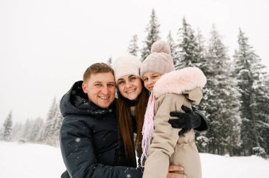 Kış ormanında neşeli mutlu bir ailenin portresi. Anne, baba ve kızı karla oynuyor. Birlikte vakit geçirmenin tadını çıkarıyorum. Aile kavramı