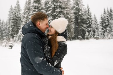 Kış yürüyüşünde birbirine sarılan sevimli bir çift. Genç bir aile, buzlu ormanda eğleniyor. Kışın romantik bir randevu. Kış Aşk Hikayesi