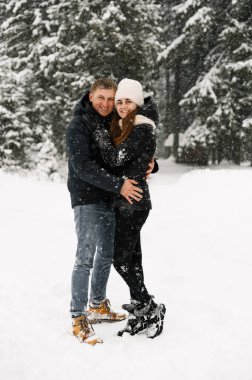 Kış yürüyüşünde birbirine sarılan sevimli bir çift. Genç bir aile, buzlu ormanda eğleniyor. Kışın romantik bir randevu. Kış Aşk Hikayesi
