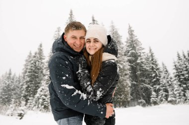 Kış yürüyüşünde birbirine sarılan sevimli bir çift. Genç bir aile, buzlu ormanda eğleniyor. Kışın romantik bir randevu. Kış Aşk Hikayesi