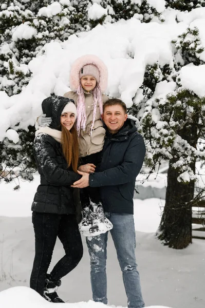 Mutlu aile kış ormanlarında eğleniyor. Anne, baba ve kızı karla oynuyorlar. Birlikte vakit geçirmenin tadını çıkarıyorlar. Aile kavramı